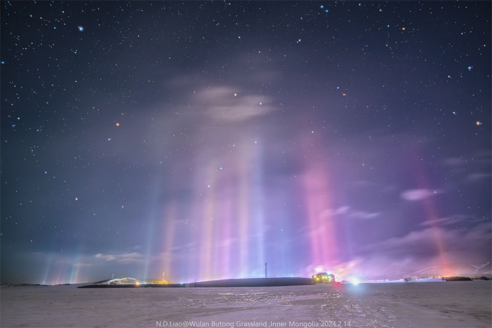 Numerous thin pillars of light connect a landscape filled
with snow to a star filled sky. The Big Dipper can be seen through
the colorful pillars.
Please see the explanation for more detailed information.