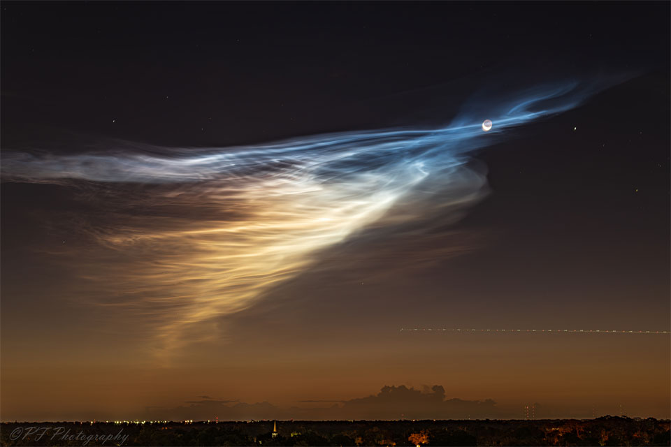 A dawn sky is shown that is black at the top and brown near the 
horizon. Wispy clouds converge on the right turning from a white to a
blue hue. Near the apex of this convergence is a crescent moon. 
Please see the explanation for more detailed information.