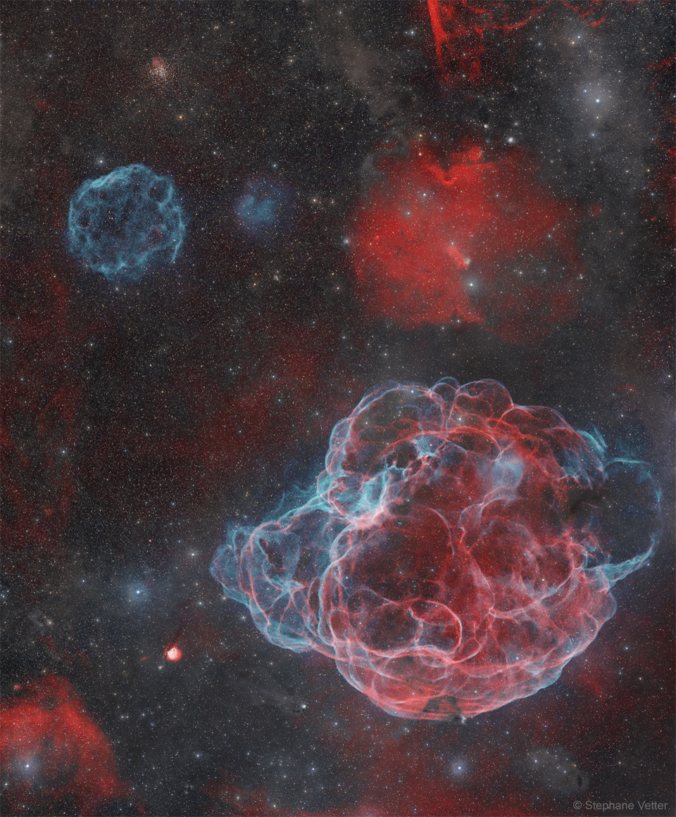 A star field appears that has several nebulas. Toward the upper
left is a angularly small supernova remnant colored blue, while 
dominating the lower right is a large supernova remnant in both
red and blue. 
Please see the explanation for more detailed information.