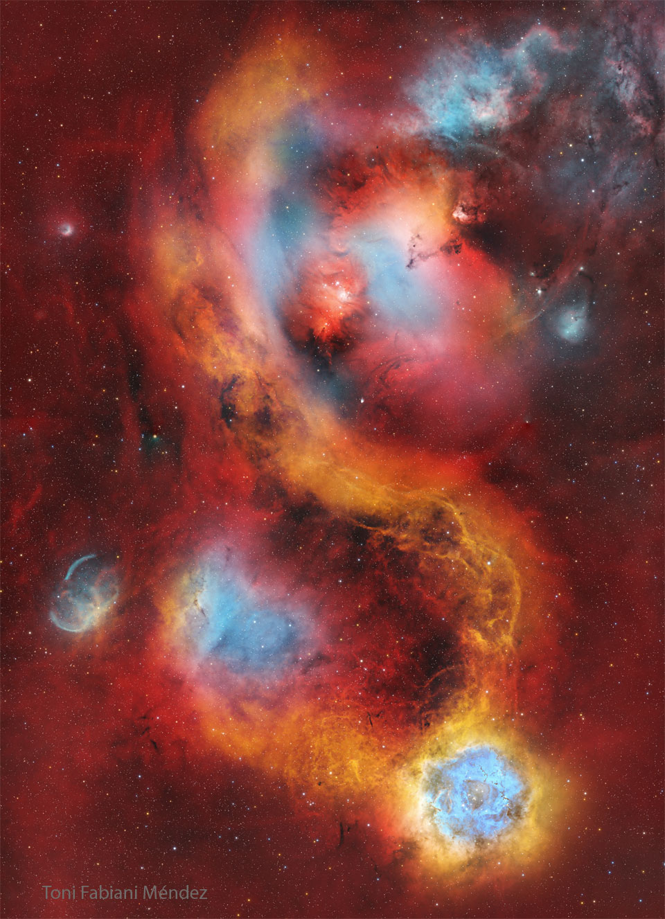 A starfield is covered with a light red glow. Several
nebulas are seen near the center. The famous Rosette nebula
appears in blue and white near the image bottom. 
Please see the explanation for more detailed information.